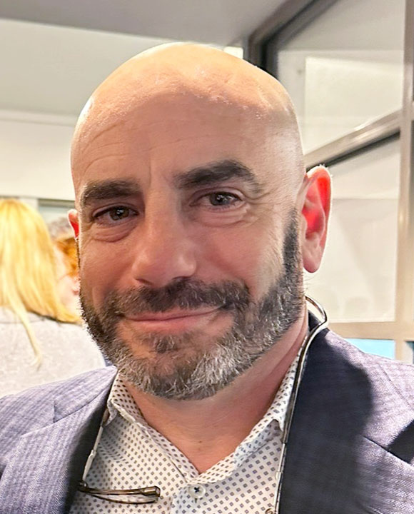 Photo of a smiling man with a beard wearing a suit